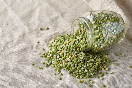 Raw green peas in glass jar over wooden background, close-up, selective focus. Some copy space for your inscription. Organic protein. Perfect ingredient for vegan cuisine. Healthy food concept. Healthy eating, dieting.の写真素材