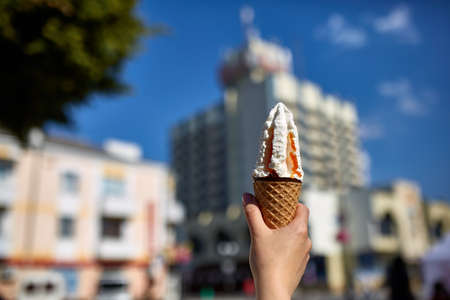 A first person view, girl walking along the road, holding ice cream in her hands and eating it in...