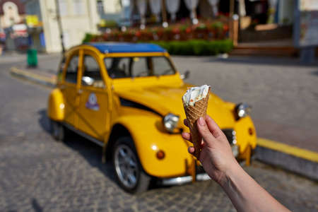 A first person view, a person walking along the road, holding ice cream in his hands and eating it...