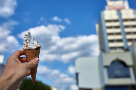 A first person view, a person walking along the road, holding ice cream in his hands and eating it...