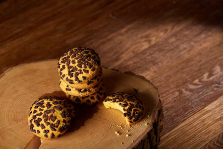 Sweet assortment of biscuits on a round wood log over rustic wooden background, close-up, selective...