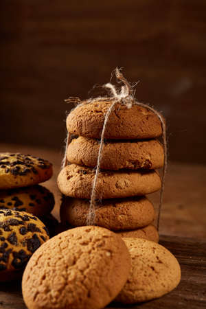 Christmas still life with assortment of cookies, cinnamon sticks and dried oranges on a round log...