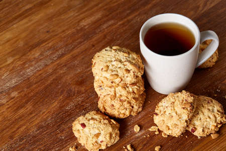 White porcelain mug of black tea or earl grey and pile of sweet cookies on rustic wooden background, top view, selective focus. Studio shot. Delicious morning beverage. Relaxing teatime. Morning concept. Healthy eating concept.の写真素材