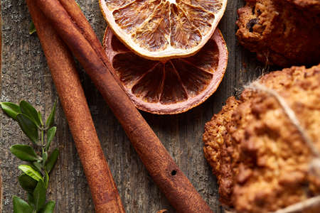 Beautiful Christmas composition with oatmeal, chocolate biscuits, cinnamon sticks and dried oranges, on rustic wooden background, close-up, selective focus. Christmas concept. Festive background.の写真素材