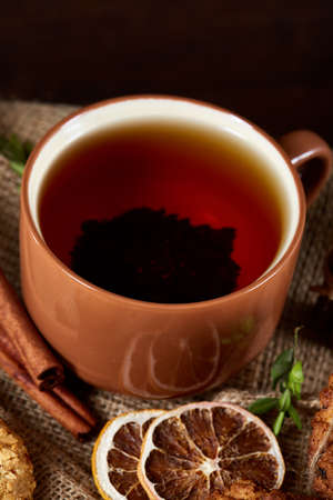 Conceptual festive composition with a cup of hot tea, a large set of cookies, cinnamon sticks bunch...