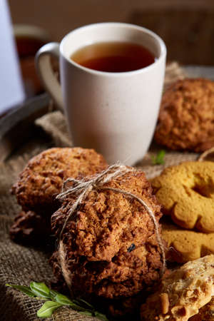 Conceptual festive composition with a cup of hot tea, a large set of cookies, cinnamon sticks bunch...