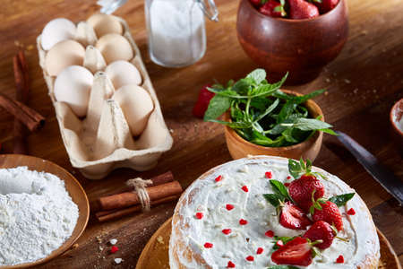 Top view raw ingredients for cooking strawberry pie or cake on wooden table: eggs, sugar, mint and...