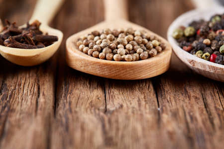 Row of wooden spoons with spices on vintage background, close-up, selective focus, vertical. Flat...