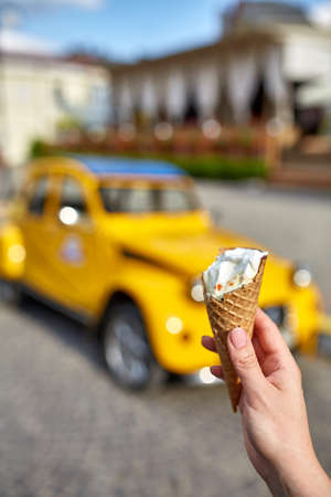 A first person view, a person walking along the road, holding ice cream in his hands and eating it...