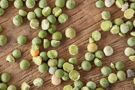 Green peas on rustic wooden background, close-up, top view, selective focus.