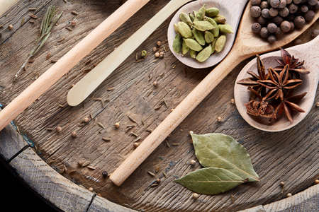 Colourful aromatic various spices for cooking on an old wooden board, close-up, flat lay, selective focus. Flat wooden spoons full of anise star, pepper seeds, clove, coriander, cumin and allspice on vintage wooden background.の写真素材