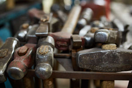 Working metal tools in blacksmith's workshop, close-up, selective focus, nobody. Various hammers in...