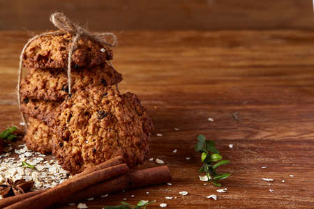 Christmas composition with sweet chocolate biscuits tied up with a ribbon, cinnamon sticks and dried oranges on rustic wooden background, close-up. Festive concept. Christmas background. Seasonal still life. Traditional Xmas composition.の写真素材
