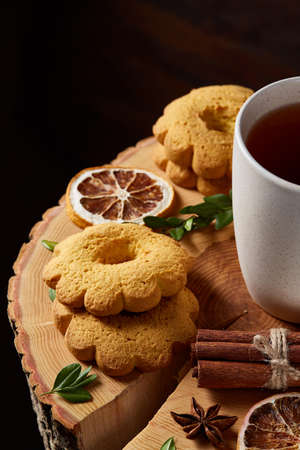 White cup of earl grey tea and sweet homemade cookies on a log over country style wooden background, close-up, selective focus. Gourmet ceylon beverage with delicious biscuits over cozy rustic background. Healthy eating concept.の写真素材