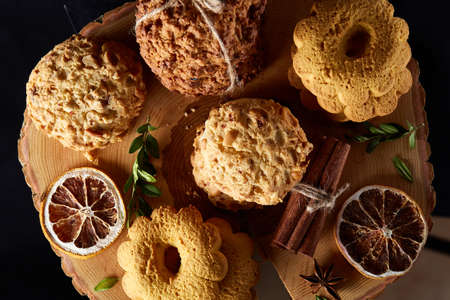 Christmas concept with sweet cookies, cinnamon sticks bunch, a couple of dried oranges, anise star...