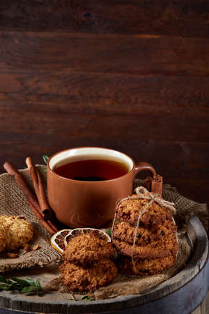 Traditional Christmas tea concept with a cup of hot tea, a large set of cookies, cinnamon sticks bunch on a wooden background, selective focus, close-up. Delicious treat. Relaxing teatime. Christmas background. Festive concept.の写真素材