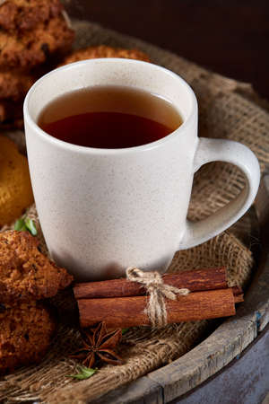 Traditional Christmas tea concept with a cup of hot tea, a large set of cookies, cinnamon sticks bunch on a wooden background, selective focus, close-up. Delicious treat. Relaxing teatime. Christmas background. Festive concept.の写真素材