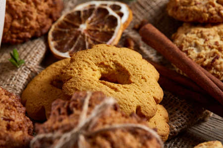 Traditional Christmas tea concept with a cup of hot tea, a large set of cookies, cinnamon sticks bunch on a wooden background, selective focus, close-up. Delicious treat. Relaxing teatime. Christmas background. Festive concept.の写真素材