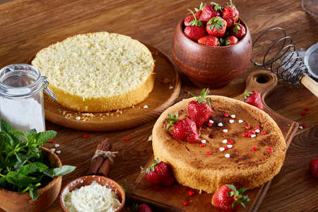 Delicious cake with fresh organic strawberries on cutting board over wooden background, top view, close-up, selctive focus. Sweet homemade dessert on wooden table. Rustic background. Tasty morning pastry. Homemade food concept.の写真素材