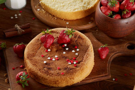 Delicious cake with fresh organic strawberries on cutting board over wooden background, top view, close-up, selctive focus. Sweet homemade dessert on wooden table. Rustic background. Tasty morning pastry. Homemade food concept.の写真素材