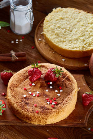 Delicious cake with fresh organic strawberries on cutting board over wooden background, top view, close-up, selctive focus. Sweet homemade dessert on wooden table. Rustic background. Tasty morning pastry. Homemade food concept.の写真素材