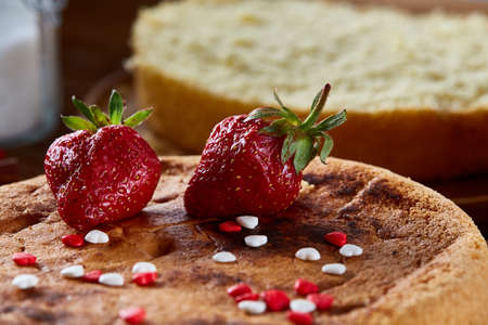 Delicious cake with fresh organic strawberries on cutting board over wooden background, top view, close-up, selctive focus. Sweet homemade dessert on wooden table. Rustic background. Tasty morning pastry. Homemade food concept.の写真素材