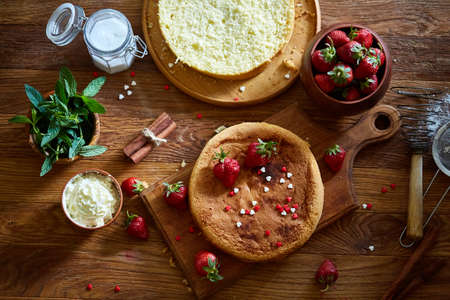 Delicious cake with fresh organic strawberries on cutting board over wooden background, top view, close-up, selctive focus. Sweet homemade dessert on wooden table. Rustic background. Tasty morning pastry. Homemade food concept.の写真素材