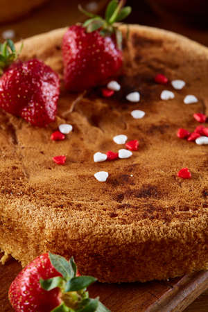 Delicious cake with fresh organic strawberries on cutting board over wooden background, top view, close-up, selctive focus. Sweet homemade dessert on wooden table. Rustic background. Tasty morning pastry. Homemade food concept.の写真素材
