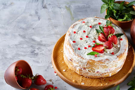Tart with strawberries and whipped cream decorated with mint leaves on white textured background, top view, selective focus, shallow depth of field. Some copy space for your text. Tasty morning pastry. Homemade food concept. Bakery background.の写真素材