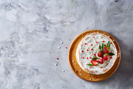 Tart with strawberries and whipped cream decorated with mint leaves on white textured background,...