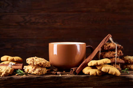 Sweet Christmas teatime with oatmeal, chocolate biscuits, cinnamon sticks and dried oranges, on rustic wooden background, close-up, selective focus. Christmas concept. Festive background.の写真素材