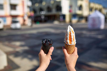 A first person view, female walking along the road with an ice cream in her hands, shallow depth of...