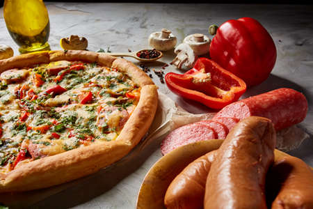 Part of tasty Italian pizza and its ingredients on white textured background, top view, close-up, selective focus. Delicious snack. Traditional homemade Italian pizza. Mediterranian cuisine. Fast food concept.の写真素材
