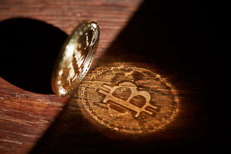 Bitcoin cryptocurrency with its shadow on wooden table, close-up, macro, selective focus, shallow depth of field. Some copy space for your inscription. Electronic commerce. Cryptocurrency concept.の写真素材