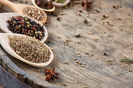 Colourful aromatic various spices for cooking on an old wooden board, close-up, flat lay, selective focus. Flat wooden spoons full of anise star, cardamon, clove, coriander, cumin and allspice on vintage wooden background. Healthy eating concept.の写真素材