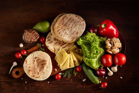 Juicy still life with pork chops, vegetables and sauces on a cutting board over a wooden background, top view.の写真素材