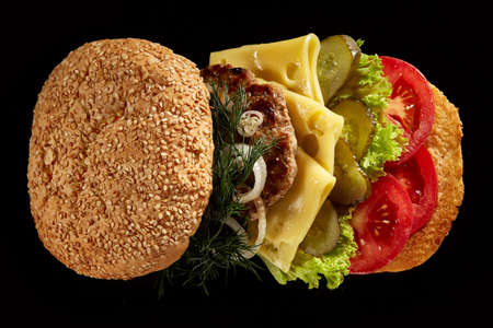 Big fresh burger with sauce arranged on black square plate on black wooden background, flat lay, close-up, selective focus. American classic burger menu. Artistic serving. Nutritious junk food. Fast food concept.の写真素材