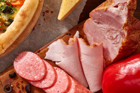 Pizza still life. Freshly baked Italian pizza and its components arranged on wooden background, top view, close-up, selective focus. Delicious snack. Traditional homemade Italian pizza. Mediterranian cuisine. Fast food concept.の写真素材