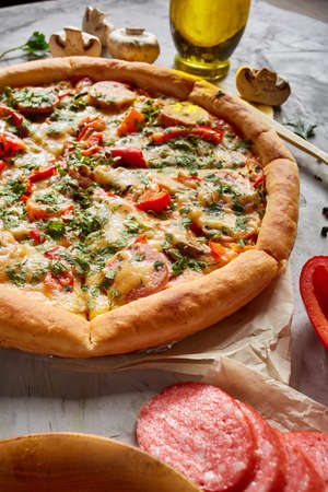 Part of tasty Italian pizza, pepper, parsley and cheese on white textured background, top view, close-up, selective focus. Delicious snack. Traditional homemade Italian pizza. Mediterranian cuisine. Fast food concept.の写真素材