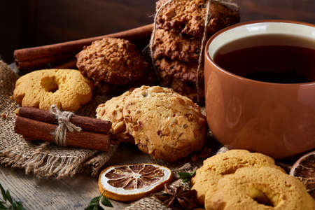 Cookies with cinnamon and two cups of tea on a burlap napkin, selective focus, close-up, top view. Delicious teatime on Christmas background. Festive concept. Sweet homemade treat.の写真素材
