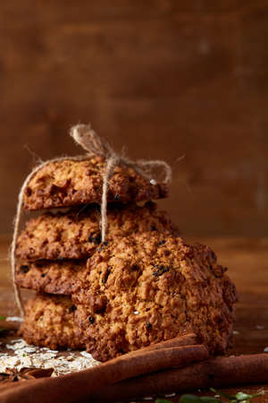 Conceptual composition with assortment of cookies, cinnamon sticks bunch and dried oranges with burlap napkin on a wooden barrel over rustic background, selective focus, close-up. Delicious treat. Relaxing teatime. Christmas background.の写真素材