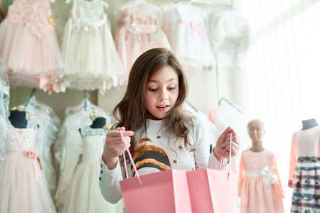 cute little girl on shopping. portrait of a kid with shopping bags. child in dress, sunglasses and shoes near shopping mall having fun. shoppingの写真素材