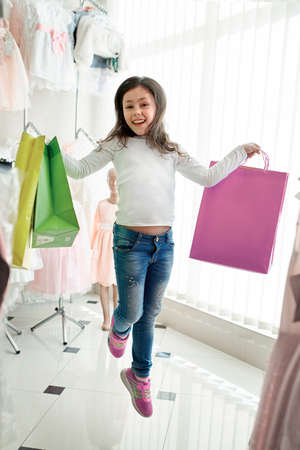 cute little girl on shopping. portrait of a kid with shopping bags. child in dress, sunglasses and shoes near shopping mall having fun. shoppingの写真素材