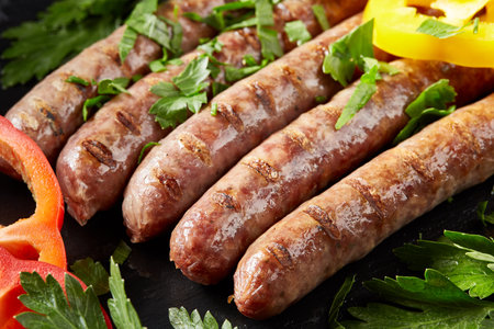 Grilling sausages on barbecue grill with greensの写真素材