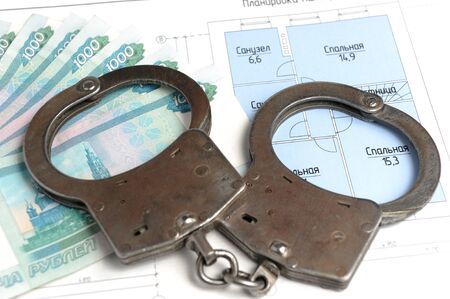 Handcuffs, money with the plan of the house on a white background