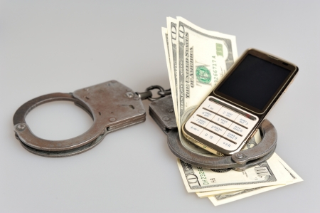 Handcuffs with mobile phone and money on gray backgroundの写真素材