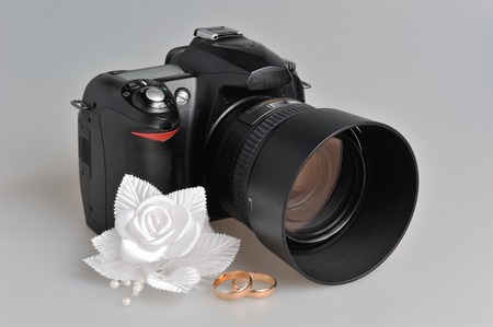 Photo camera, wedding boutonniere, rings on gray backgroundの写真素材