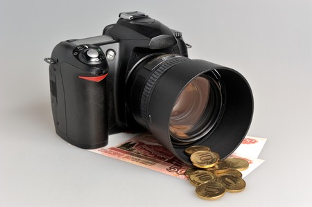 Photo camera with coins and banknotes on gray backgroundの写真素材