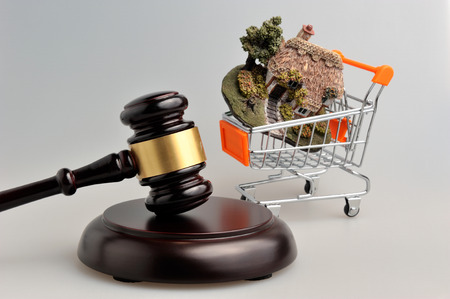 Hammer of judge with model of house in trolley on gray backgroundの写真素材