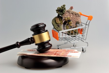 Hammer of judge with money and model of house in trolley on gray backgroundの写真素材
